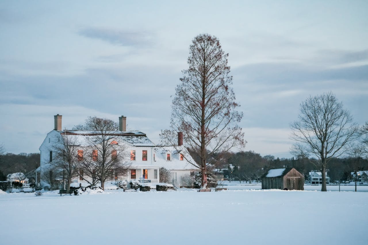 Idyllic snowy landscape with a rustic house bathed in soft evening light.