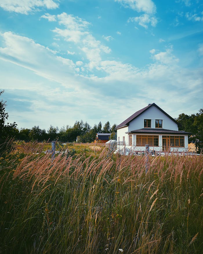 Picturesque countryside house with a cloudy sky and lush grass fields, ideal for rural living concepts.